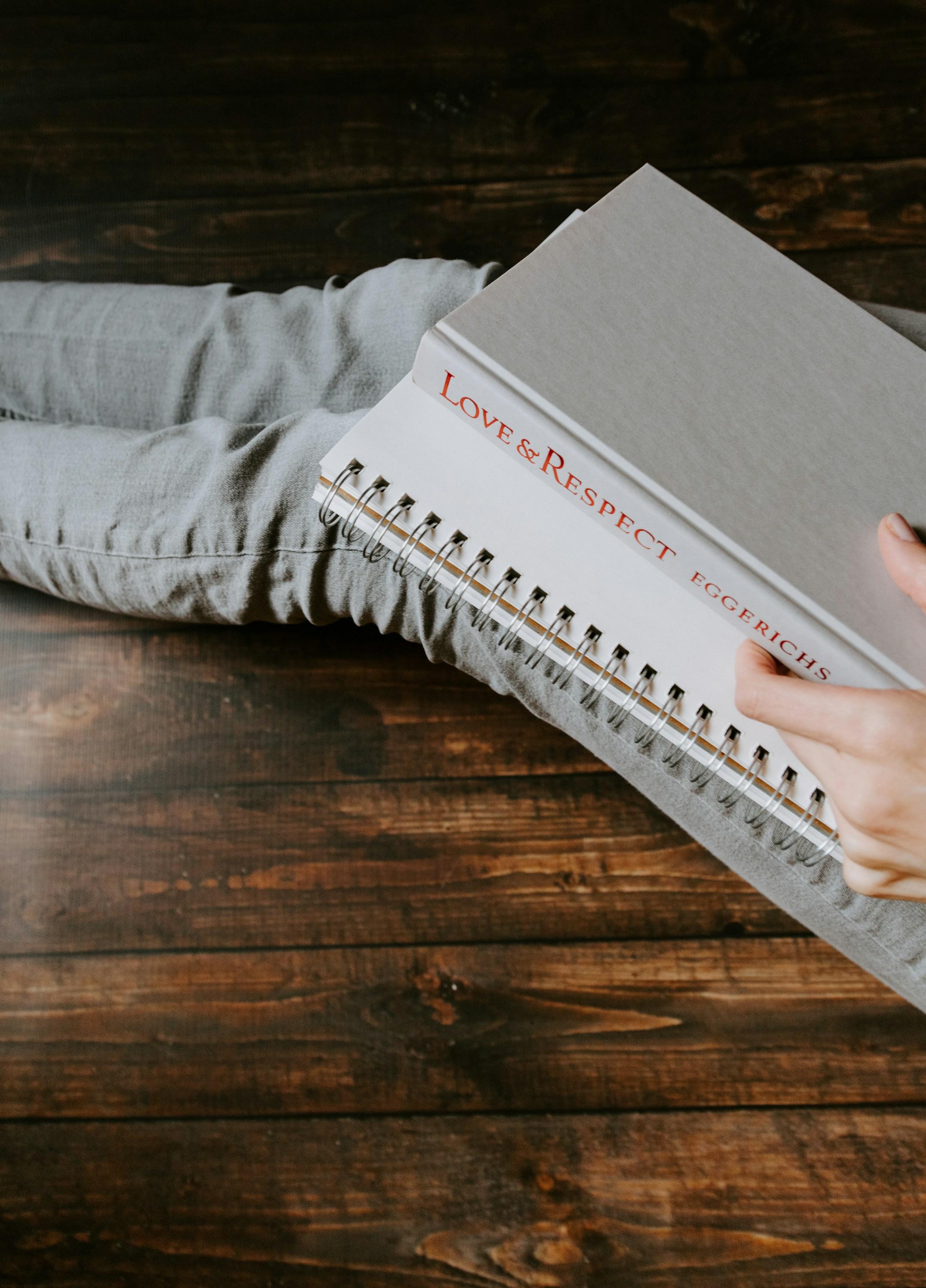 Woman's lap holding book titled "Love & Respect" and a notebook