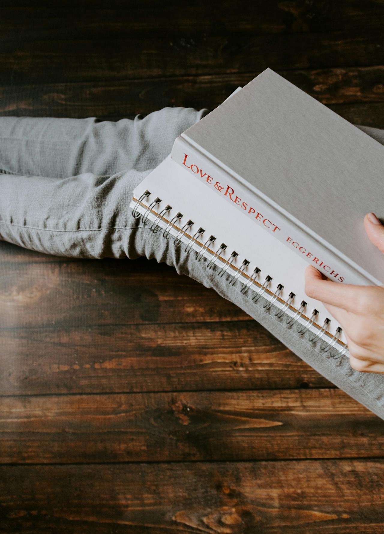 Woman's lap holding book titled "Love & Respect" and a notebook