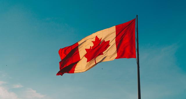 The Canadian flag raised and waving. With a good immigration lawyer in Toronto, you&#x27;ll feel right at home in Canada.