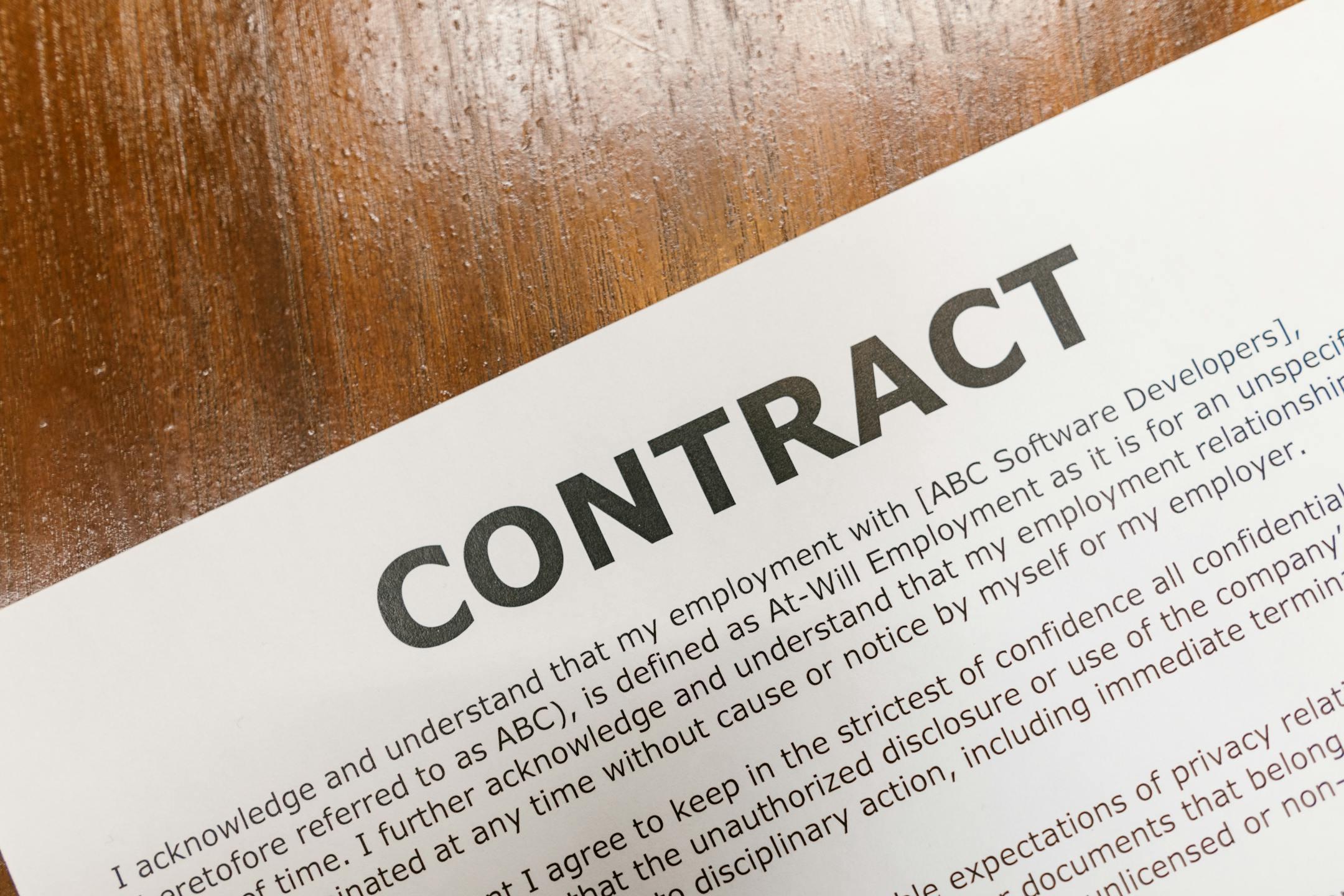 A detailed close-up of a printed contract document on a wooden table surface.