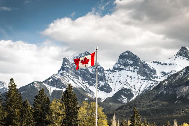Canada Canmore, Alberta. Canadian Flag with Three Sisters in the Background.