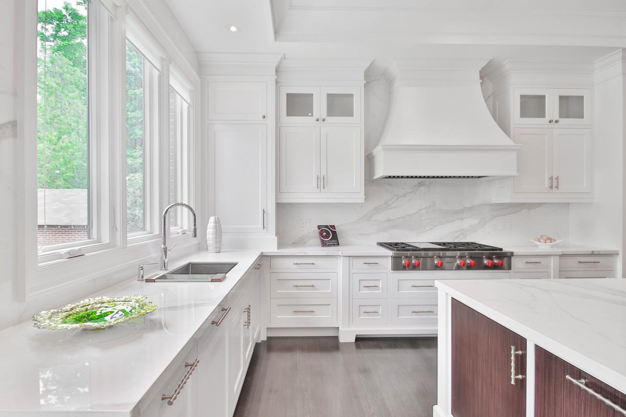 A kitchen that's compeltely white aside from brown cabinets on the island.