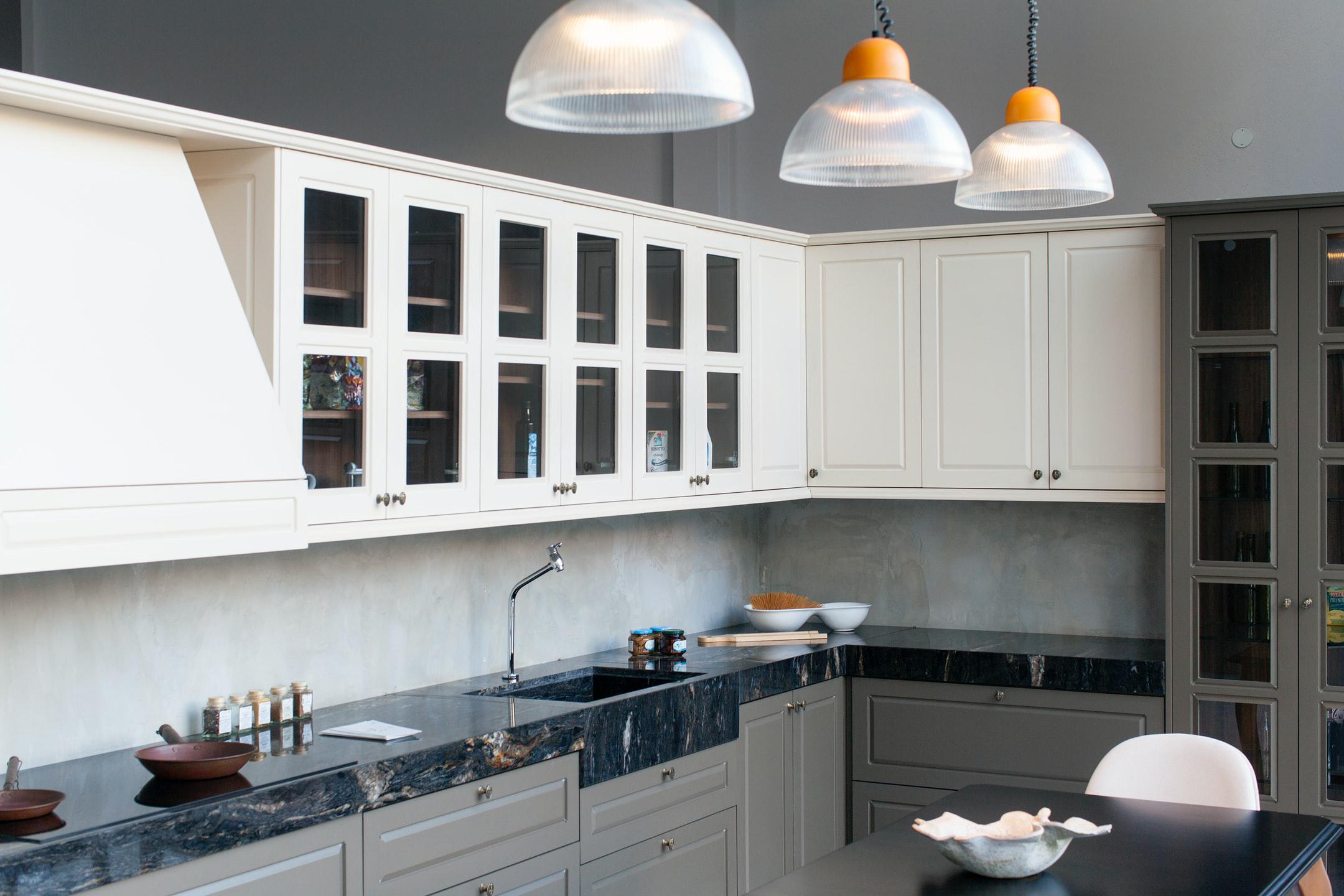 A kitchen with white cabinets and black marble countertops.