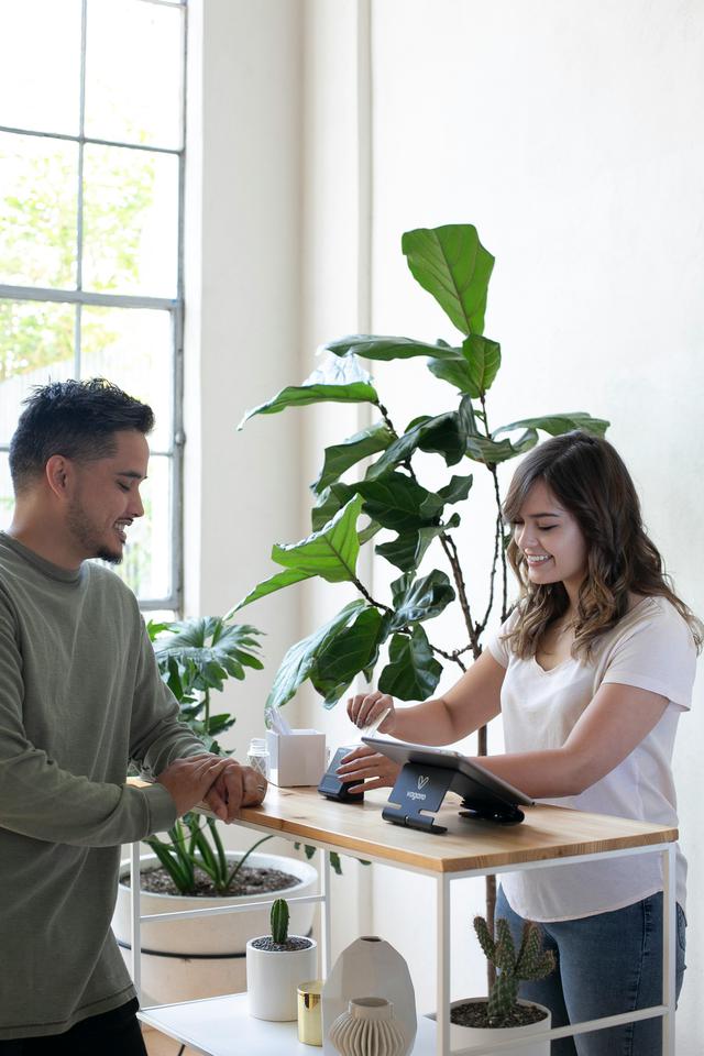 A business owner is checking out a customer with their card inserted into the Vagaro contactless card payment system. The sleek and modern payment process introduces a touch of convenience, enhancing the overall checkout experience.