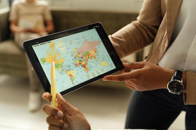 Close-up of hands holding a digital tablet displaying a world map, ideal for educational content.