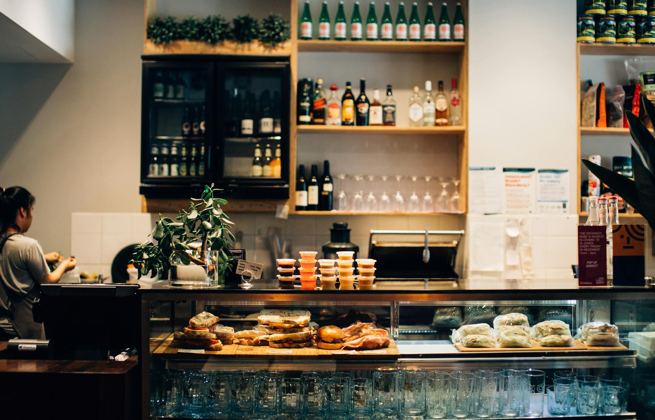 Warm café setting with sandwiches and drinks on display at the counter.