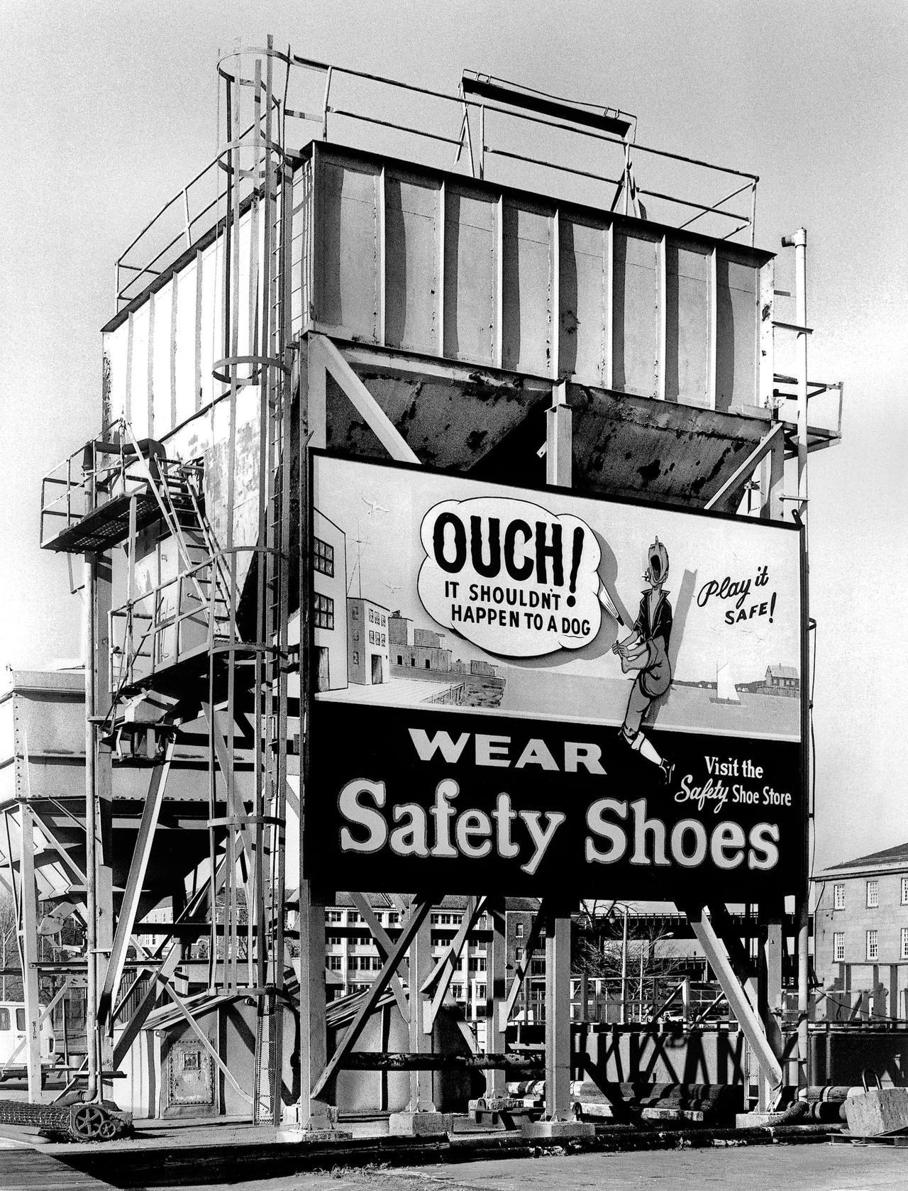 Black and white photo of a safety shoe billboard in an industrial setting, Boston.