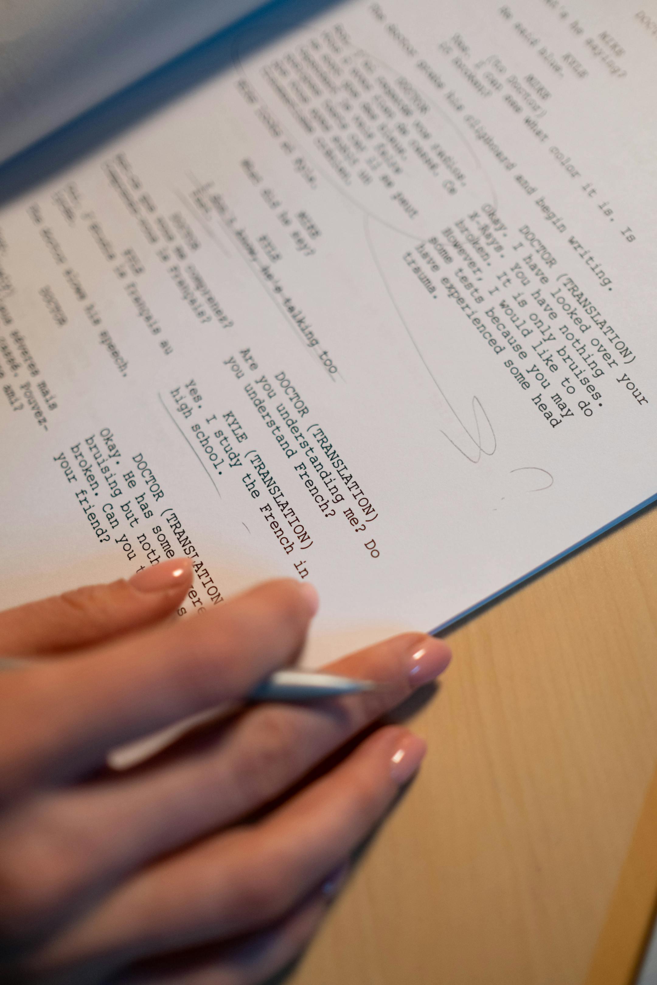 Close-up of a hand holding a pen writing notes on a screenplay document.