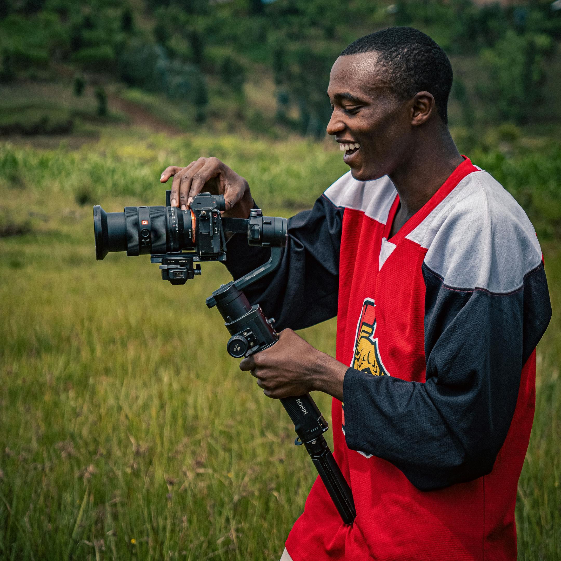 Young male photographer using a camera and gimbal outdoors, capturing scenic shots in nature.