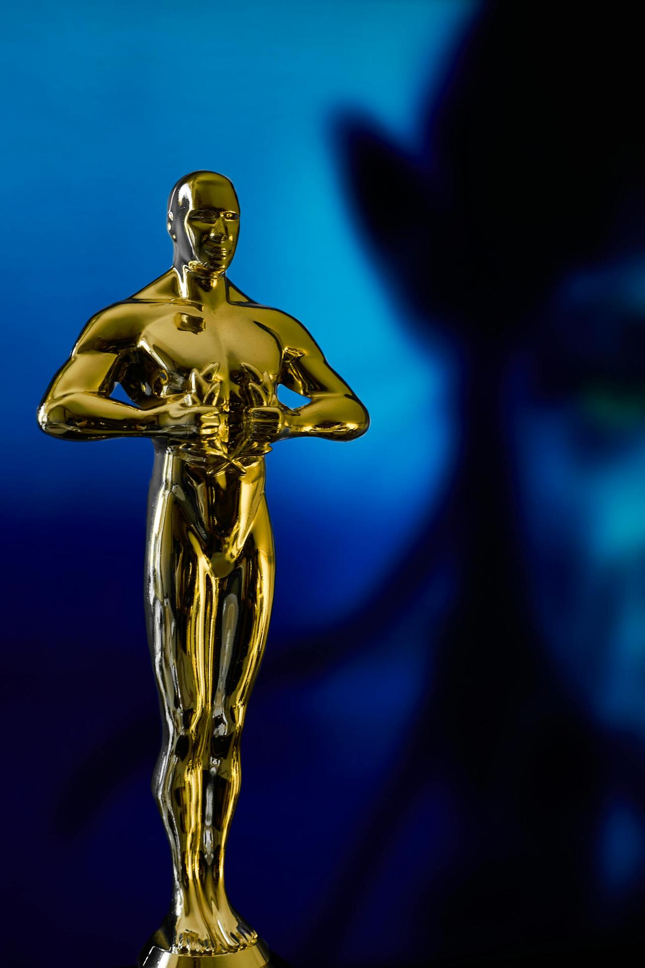 A shining Oscar statuette, symbolizing achievement in the film industry, against a vibrant blue backdrop.
