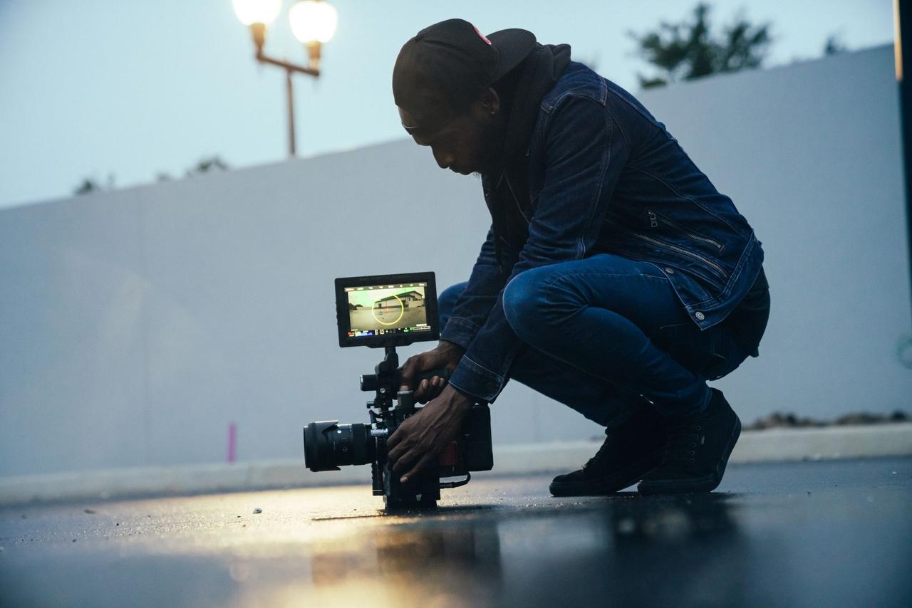 Capture of a videographer using a professional camera setup during an outdoor shoot at dusk.