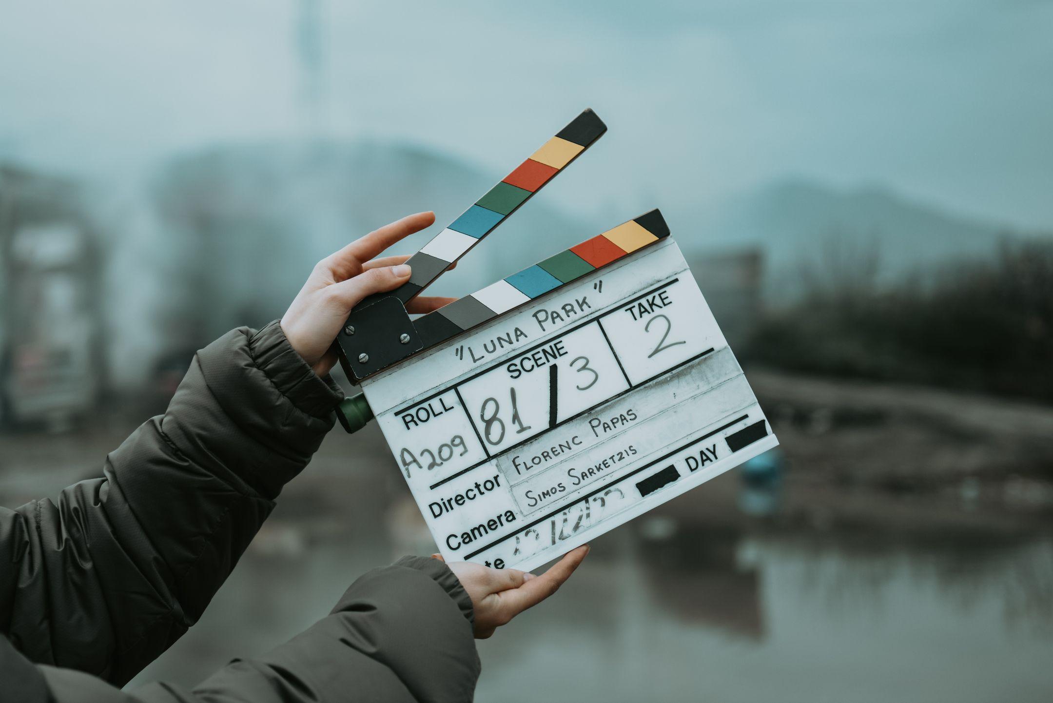 Close-up of a film clapperboard on an outdoor set, signaling scene start.