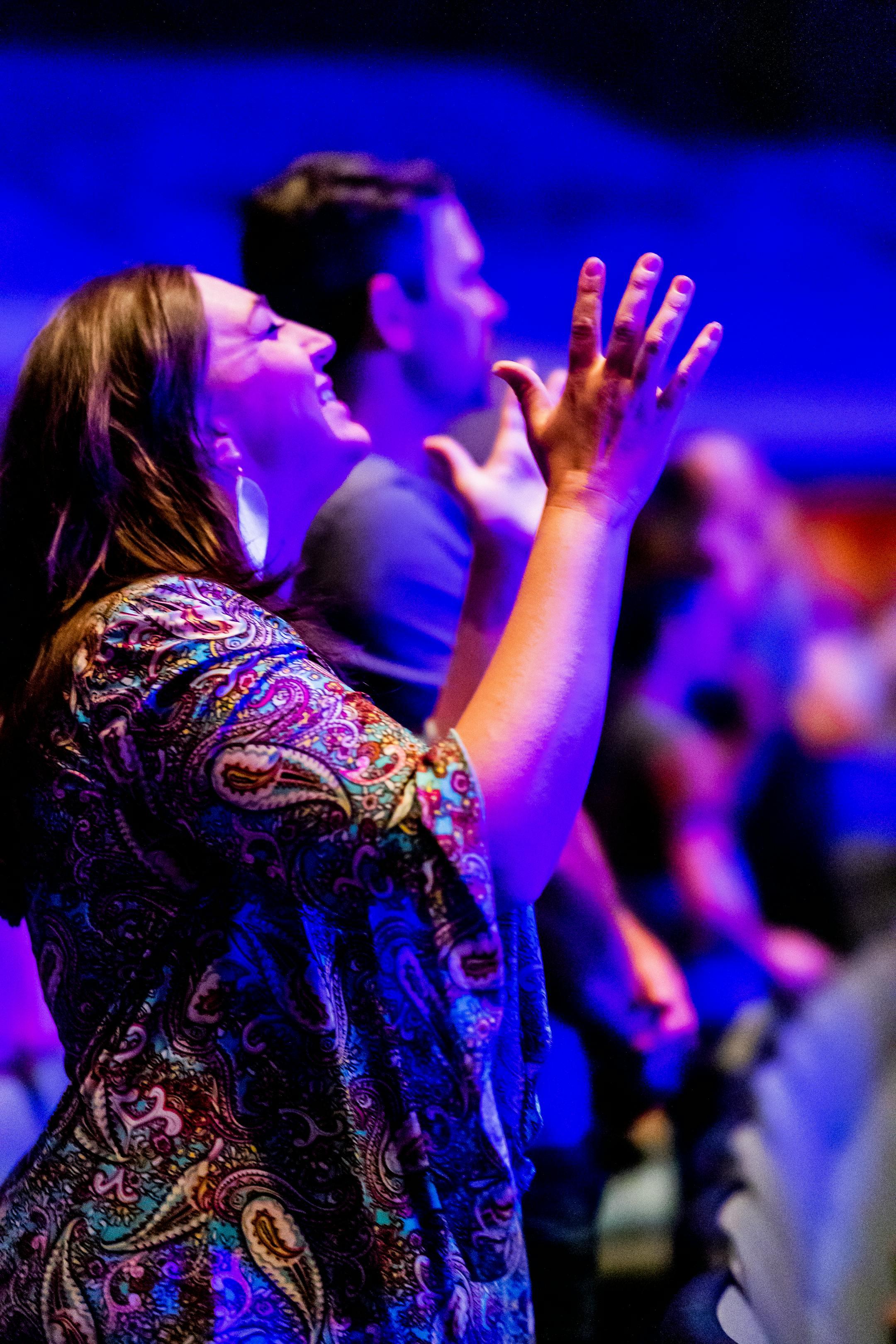 Woman enjoying live music at a vibrant concert with blue stage lights.