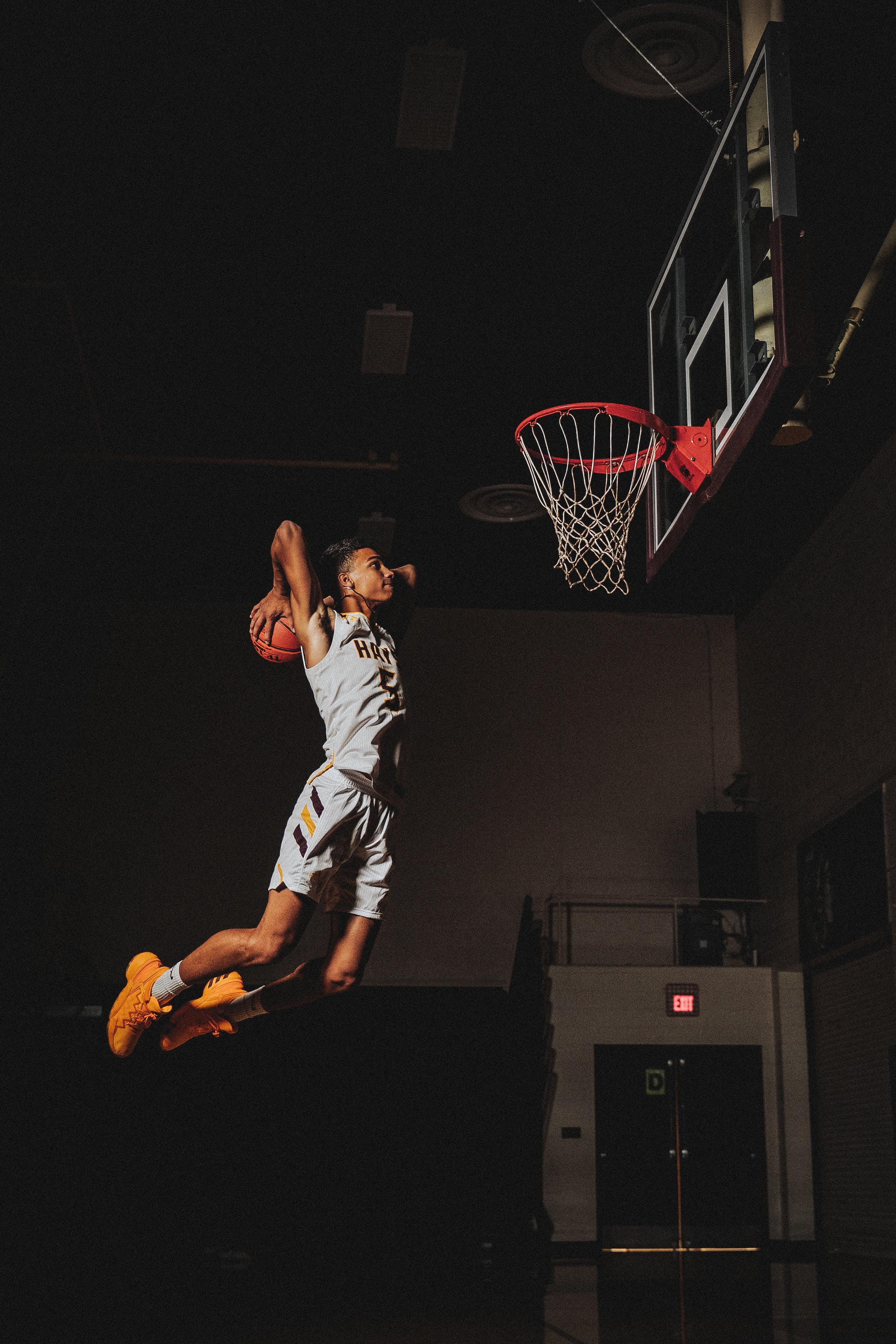 Image of a studet athlete dunking a basketball while participating in academic success programs.
