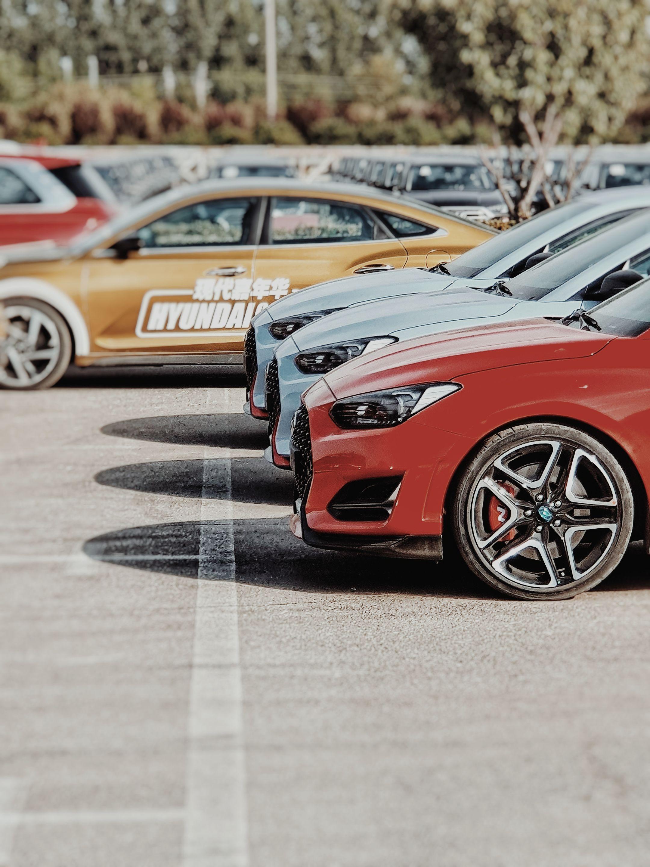 Close-up of stylish sports cars parked in a row outdoors at daytime.