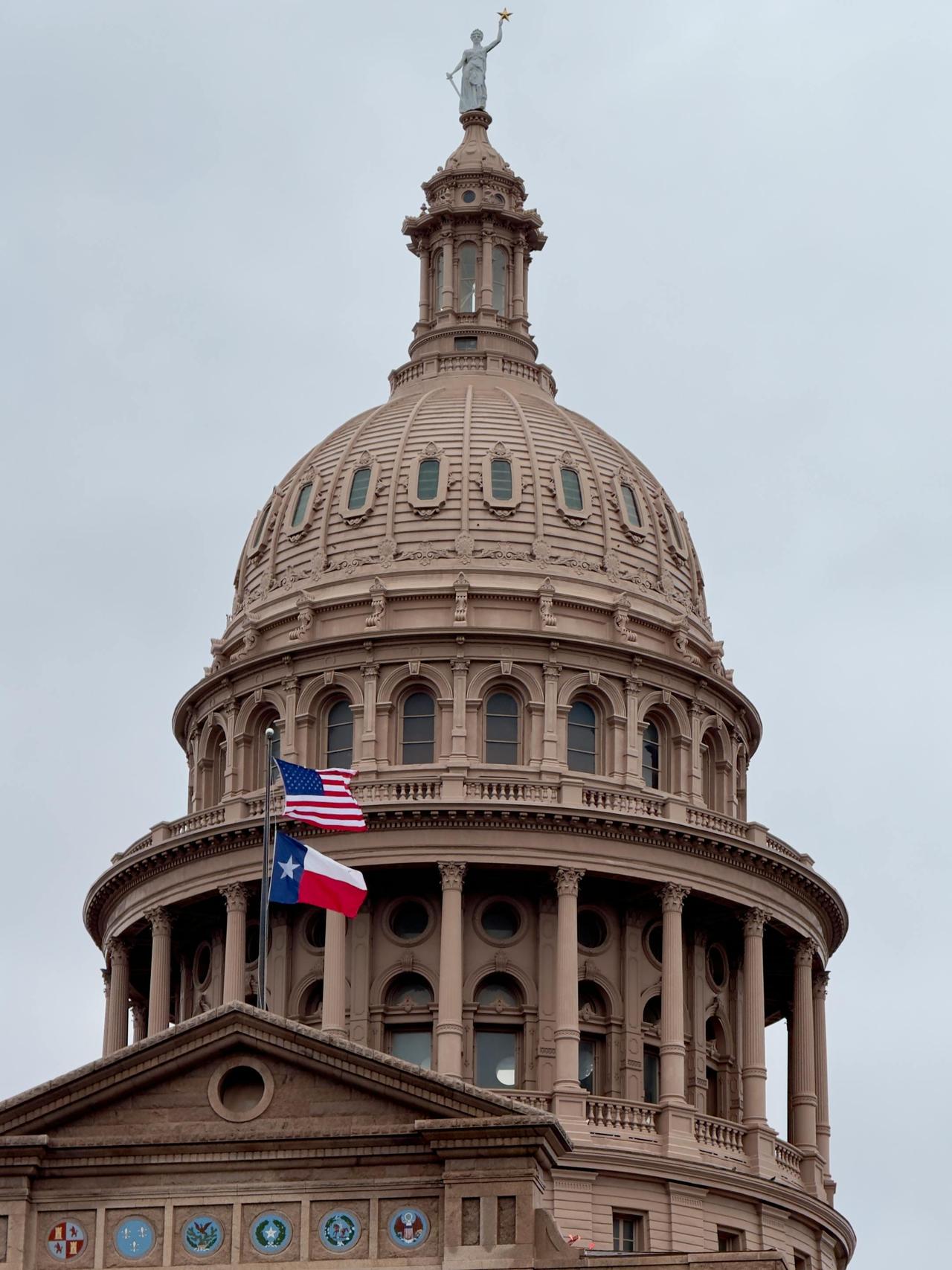 Close-up view of the Texas State Capitol dome with American and Texas flags flying.