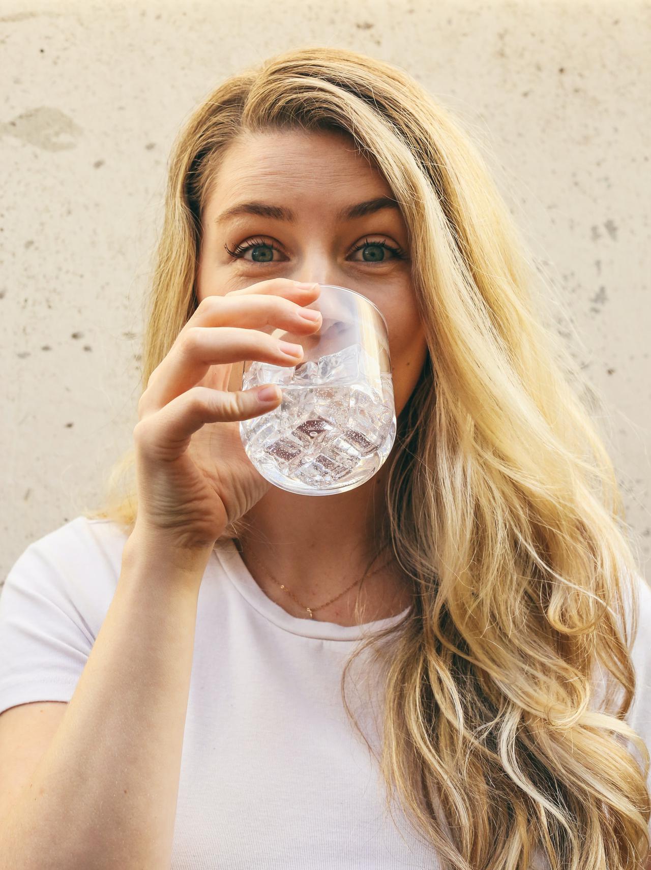 Image of a woman drinking water that's been treated by water purification experts.