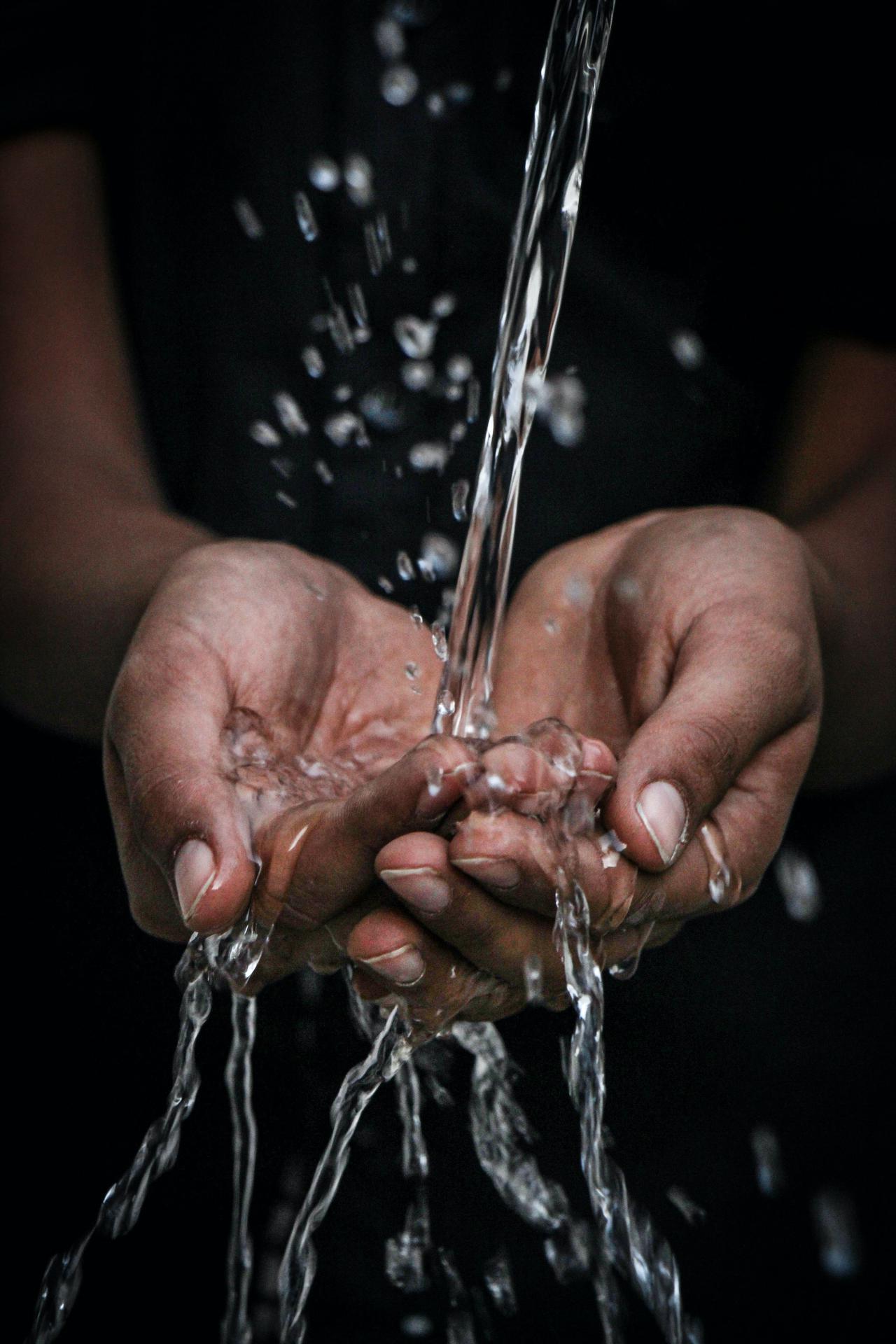 A person washing their hands with clean water.
