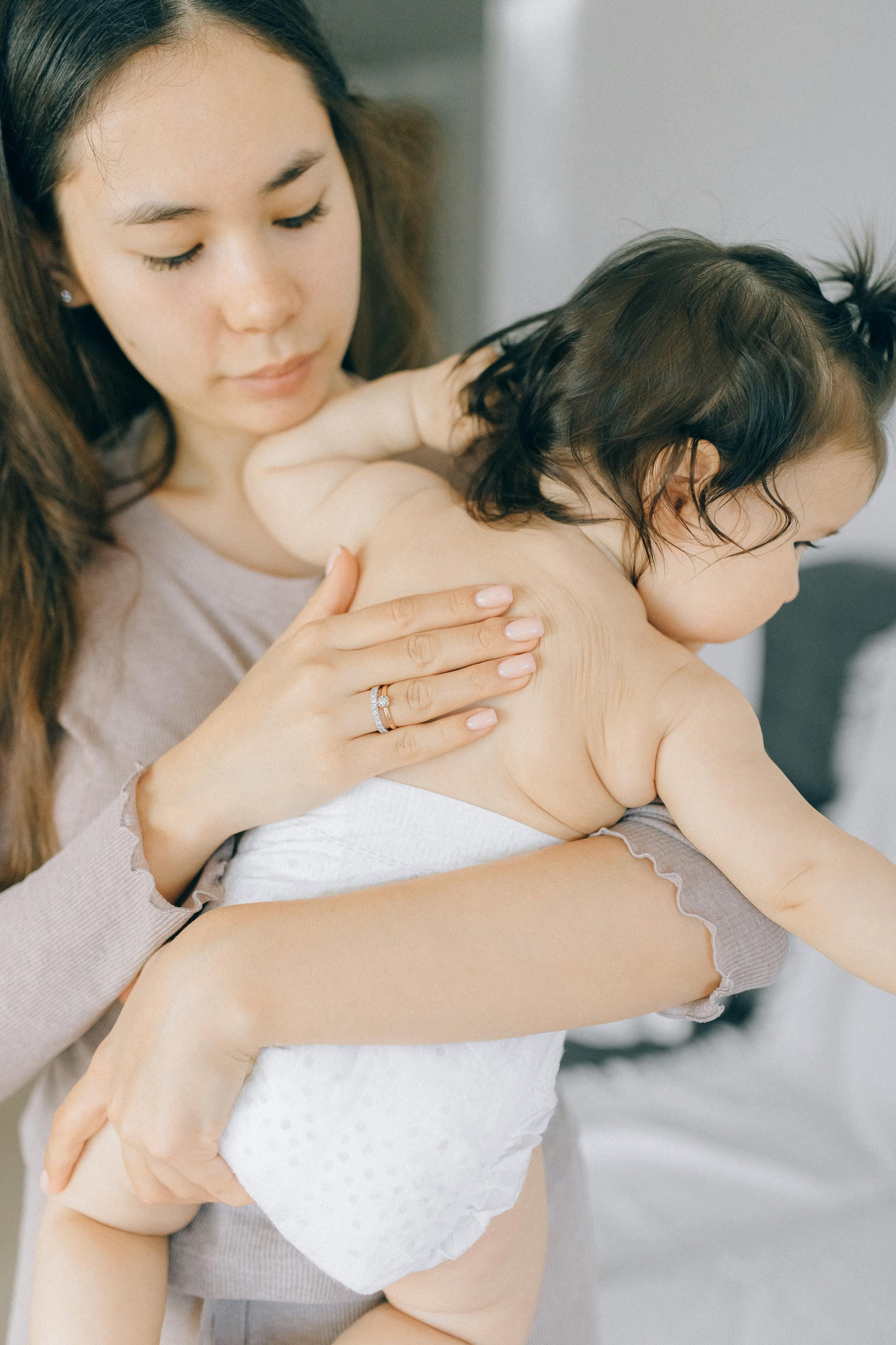 A loving mother embracing her baby in a serene indoor setting.