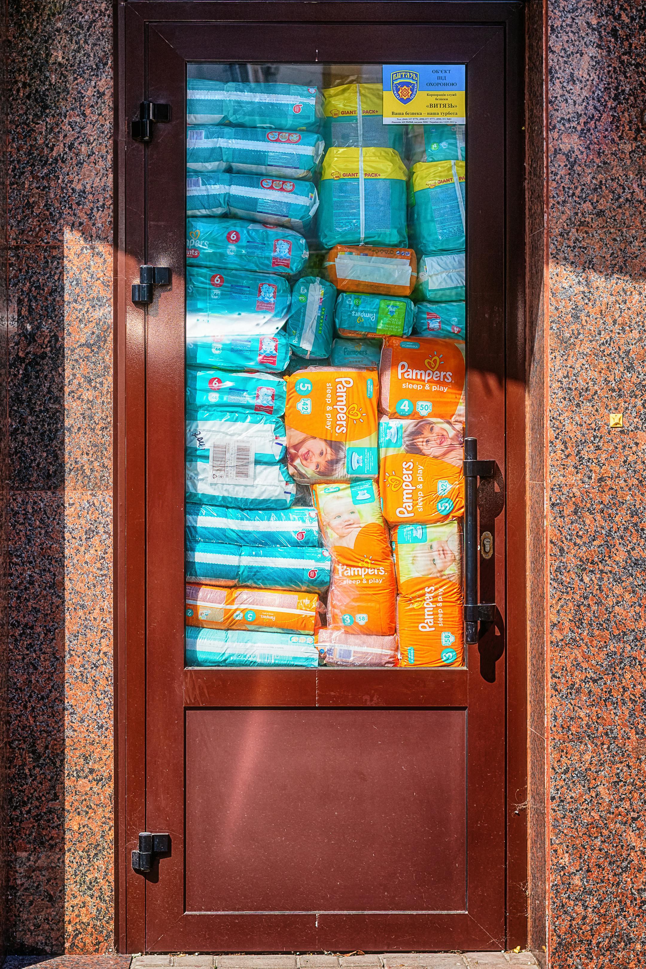 Colorful stacked diaper packages behind glass and granite door.
