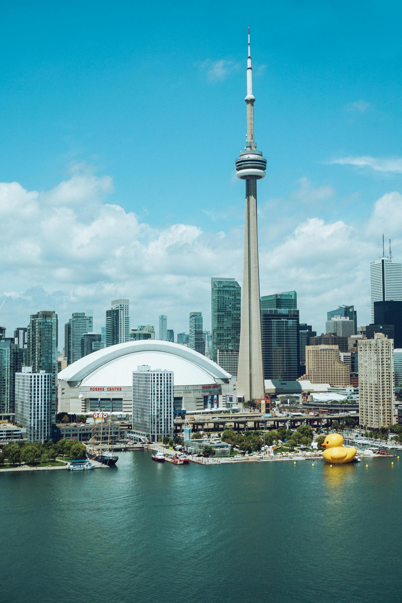 A vibrant view of Toronto's CN Tower with a scenic lakeside cityscape in the background.