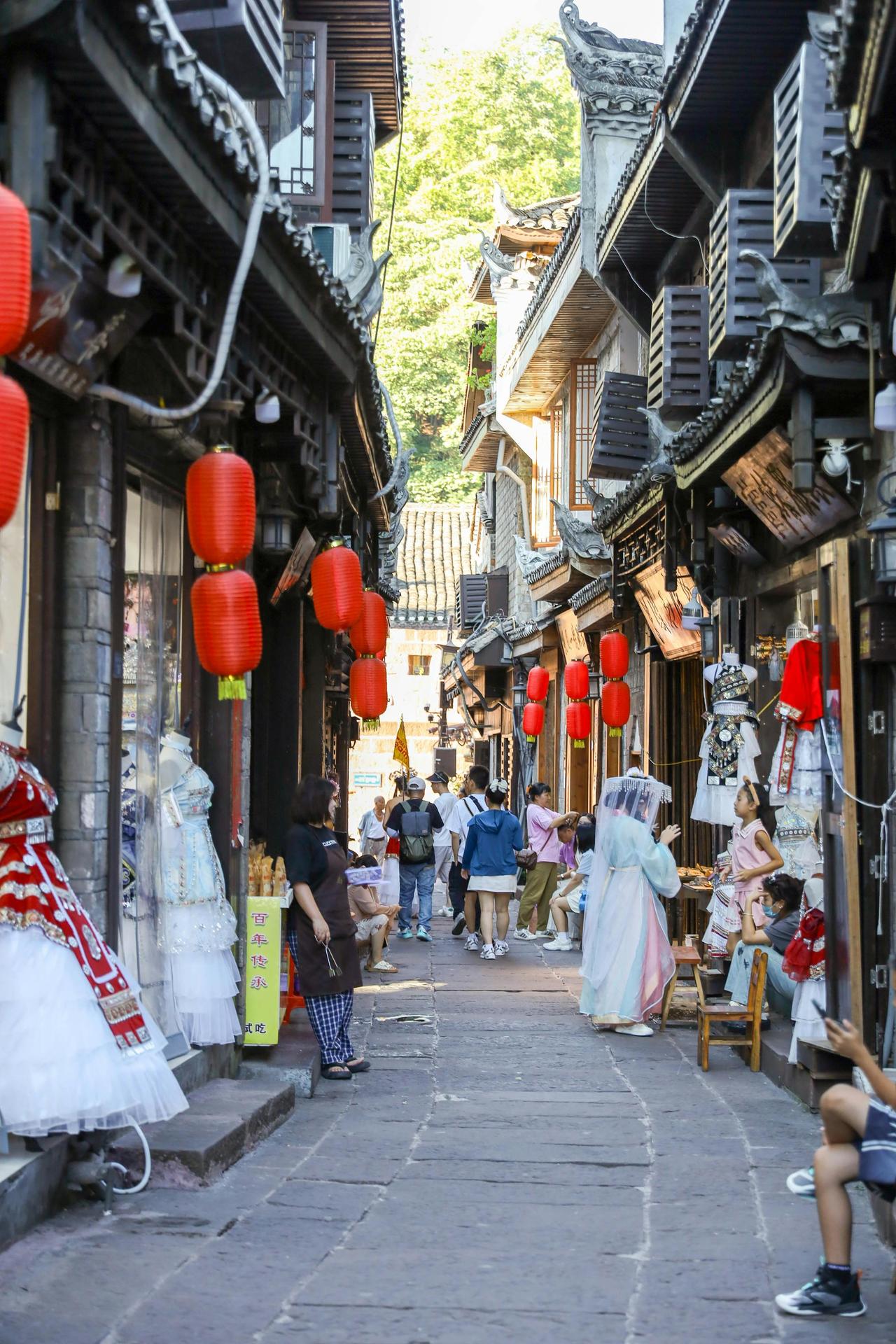 A bustling street in ancient China features red lanterns, shops, and people in traditional attire.