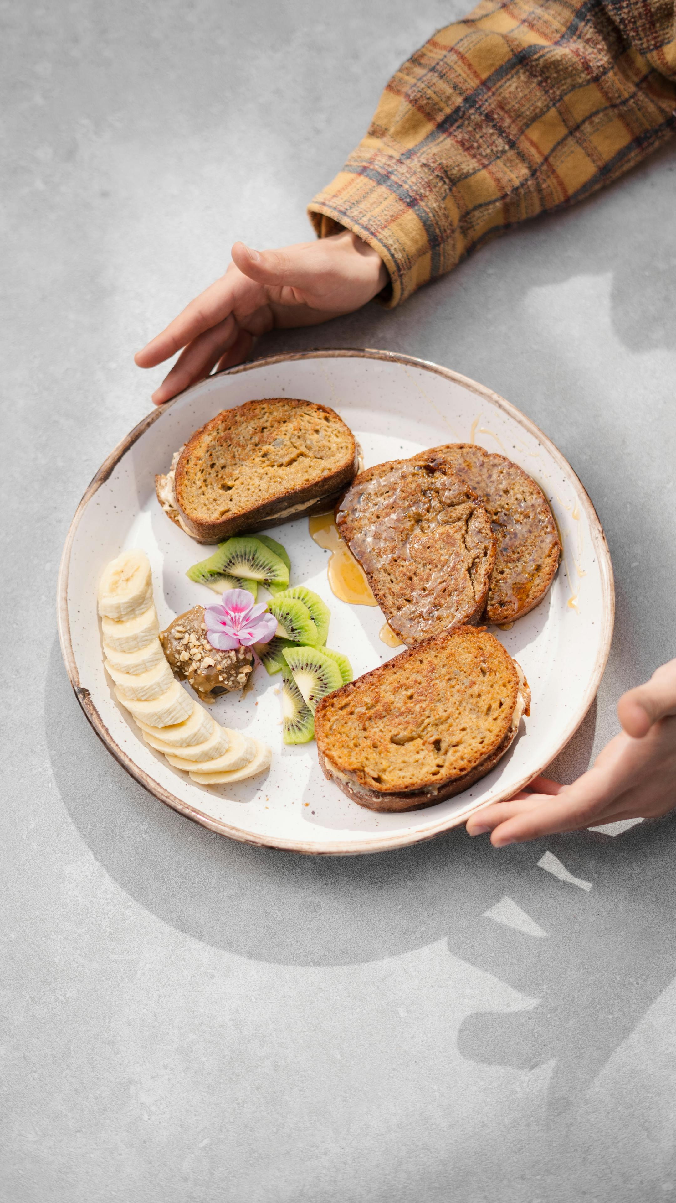 Indulge in a hearty breakfast with toasts, bananas, and kiwi on a decorative plate in Kerman, Iran.