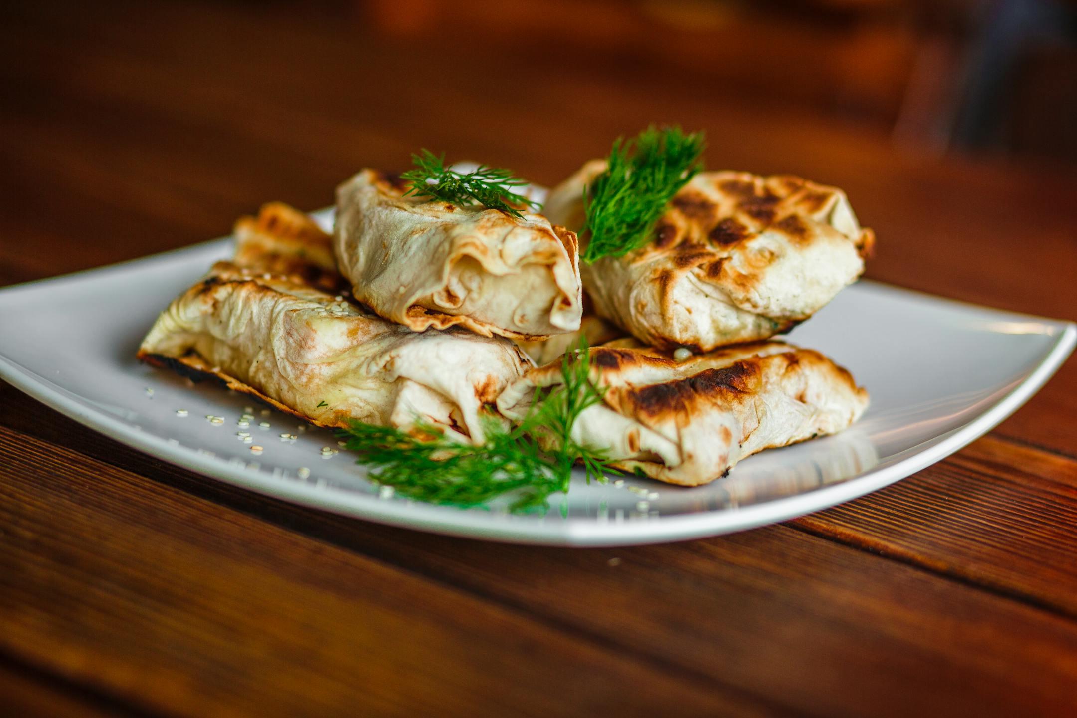 Delicious grilled wraps served on a plate with fresh dill garnish, perfect for a savory meal.