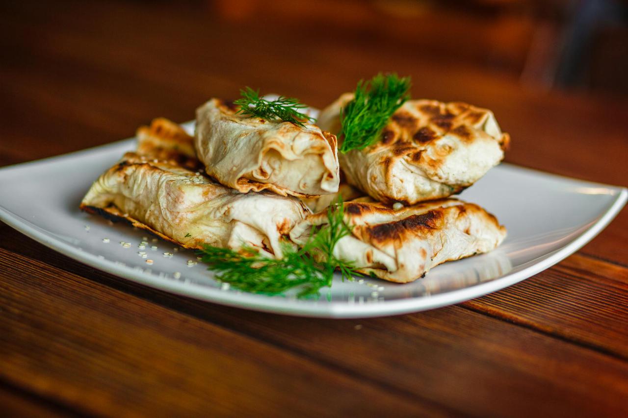 Delicious grilled wraps served on a plate with fresh dill garnish, perfect for a savory meal.