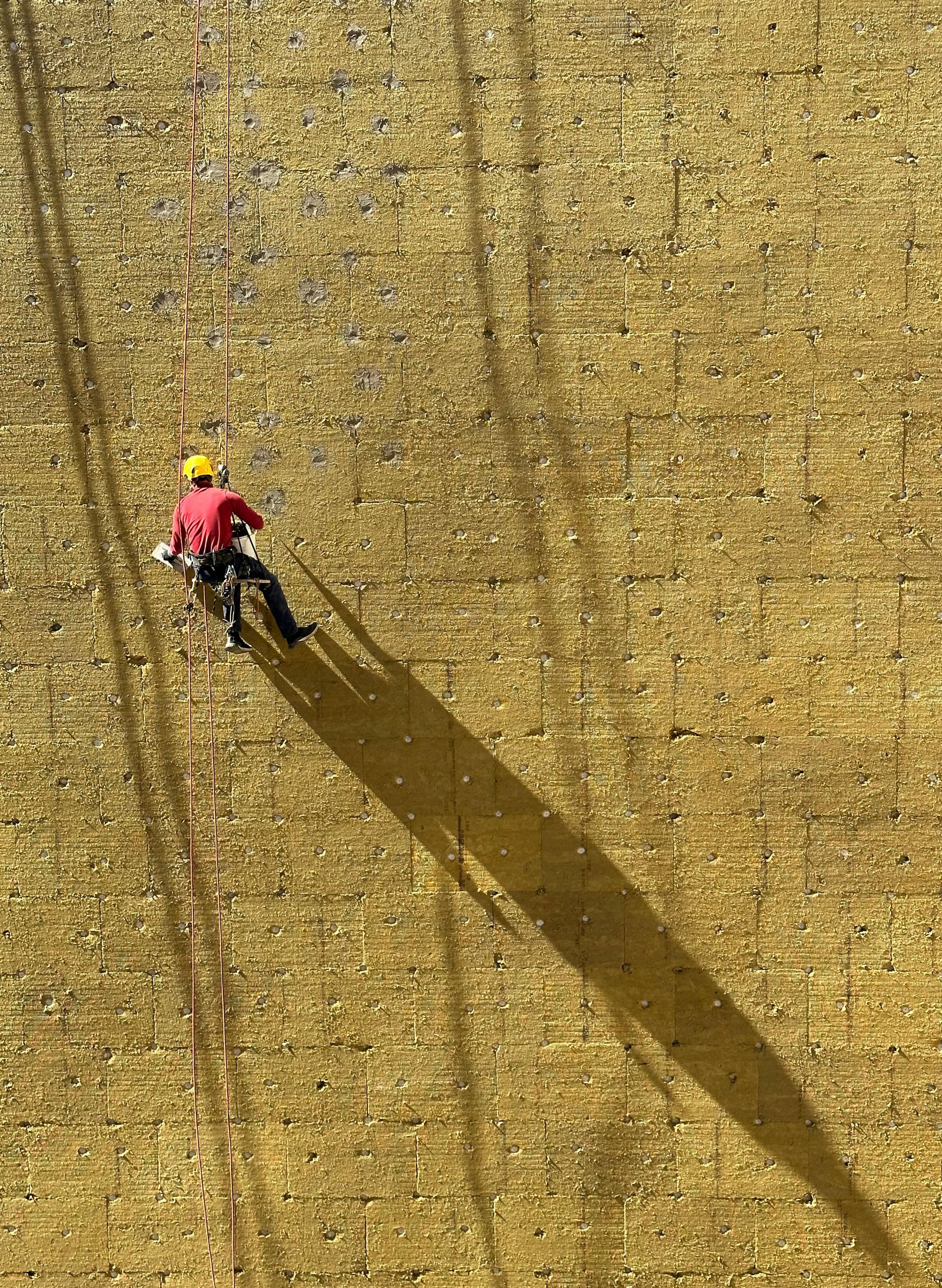 An alpinist putting insulation bricks onto the wall.