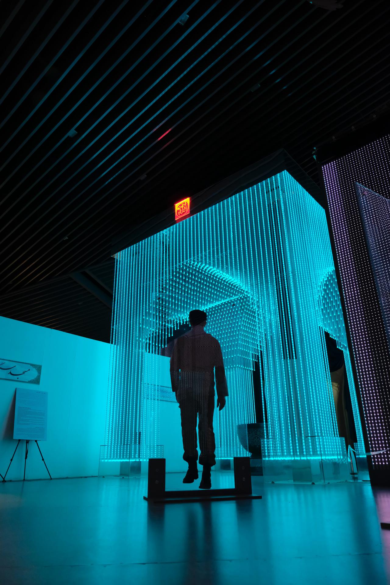 A man walking into a neon blue structure. TRACED Act compliance is the only way to protect both you and your clients.