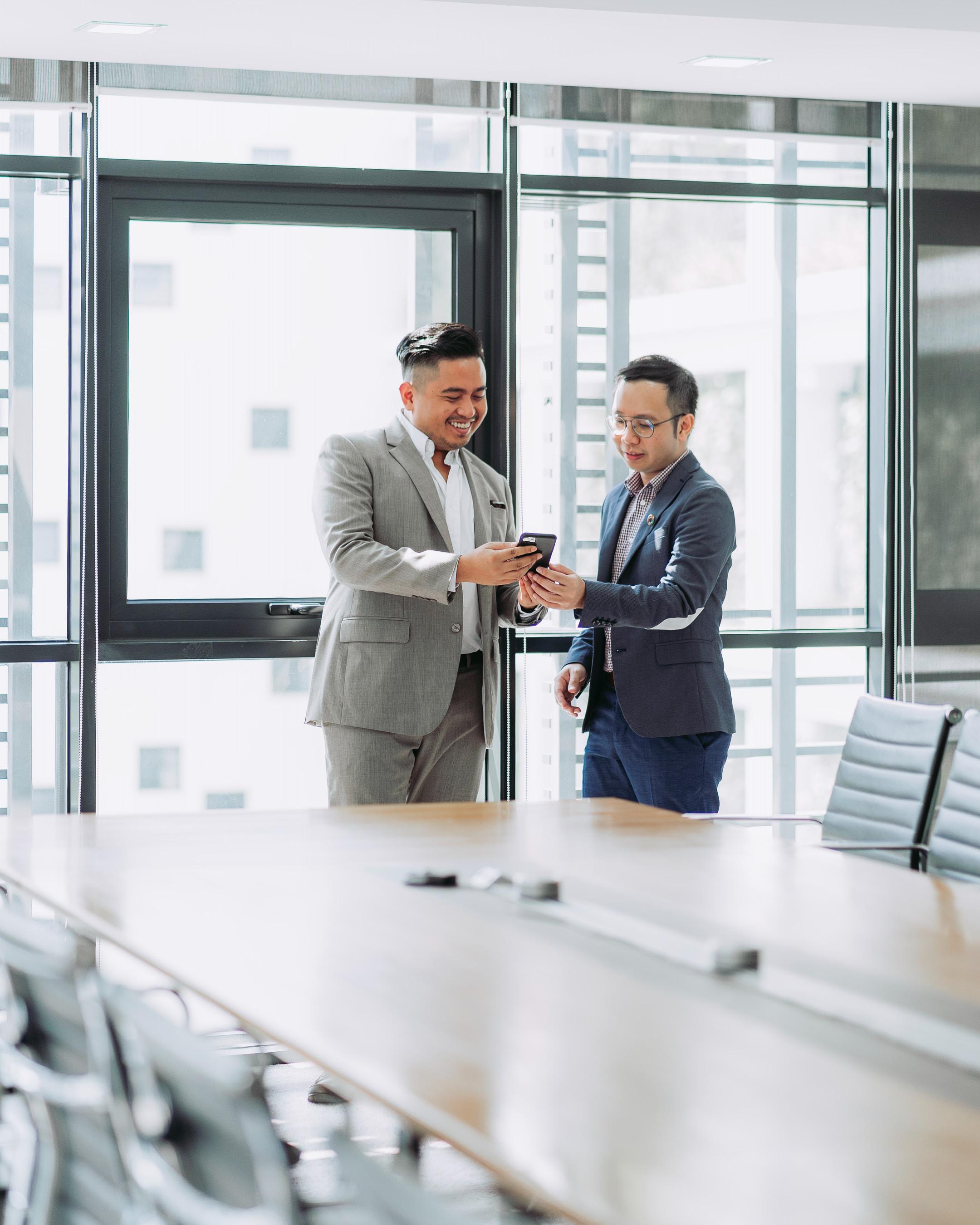 Two men looking at a phone after a business meeting. STIR-SHAKEN call authentication technology makes it more likely for everyone to answer the phone.