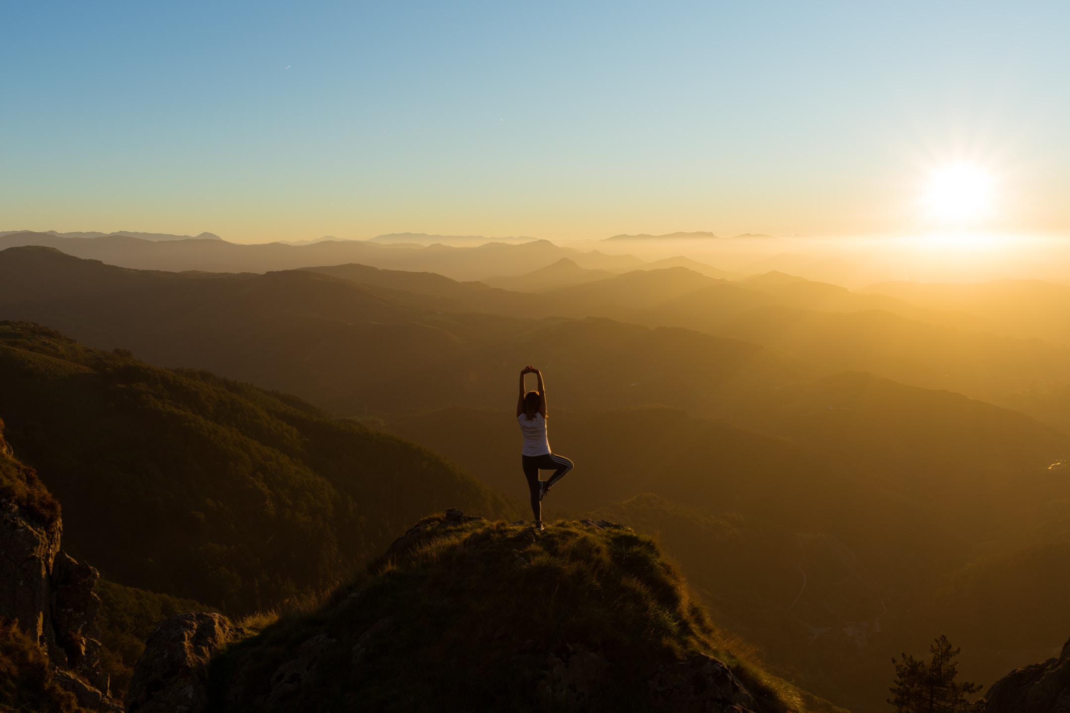 A woman performing yoga on a mountain top.
