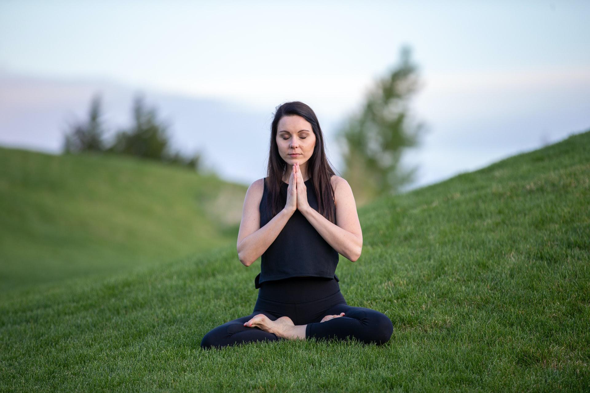 Young woman doing yoga on green grass