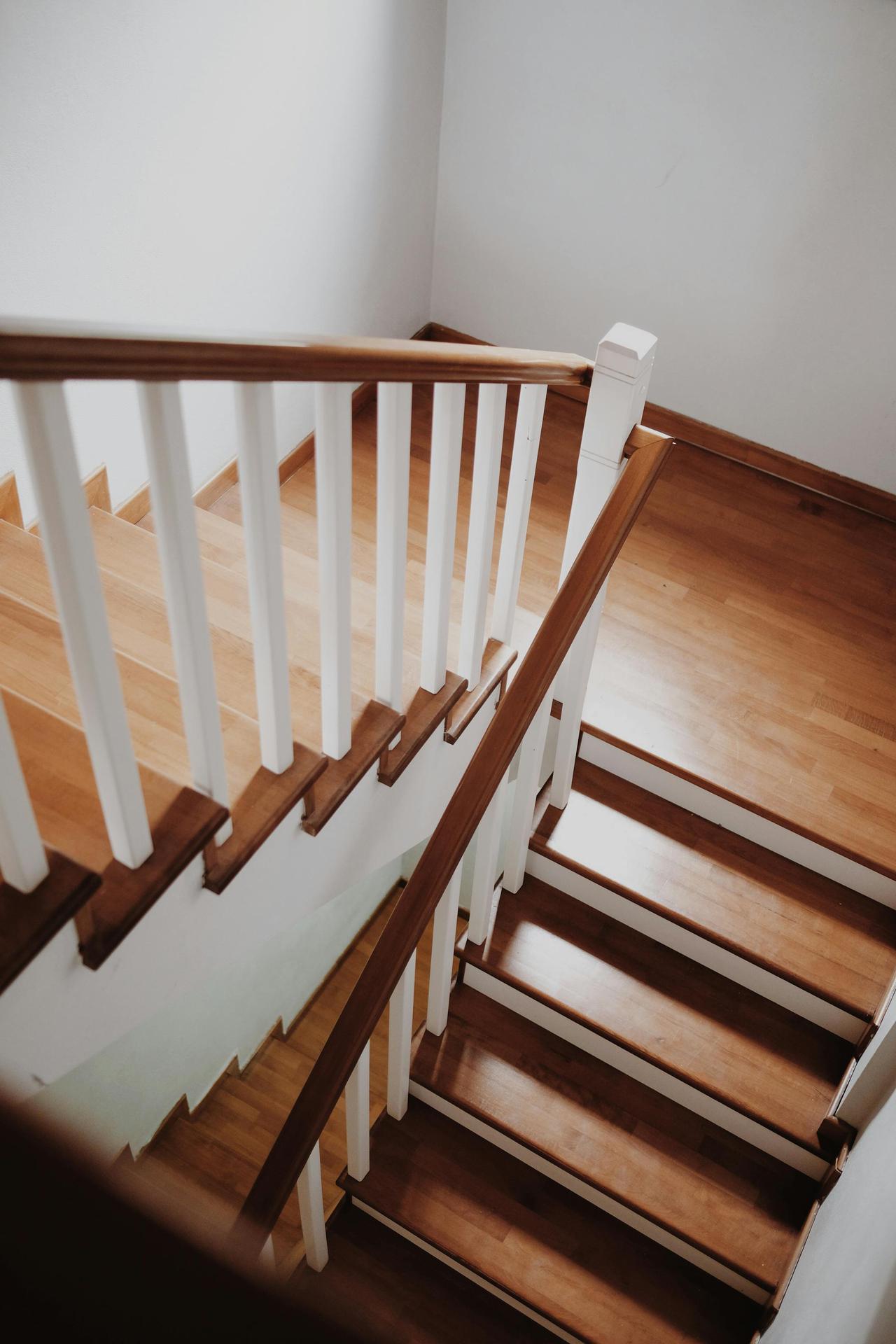 A high angle view of a modern wooden staircase in a minimalist home interior.