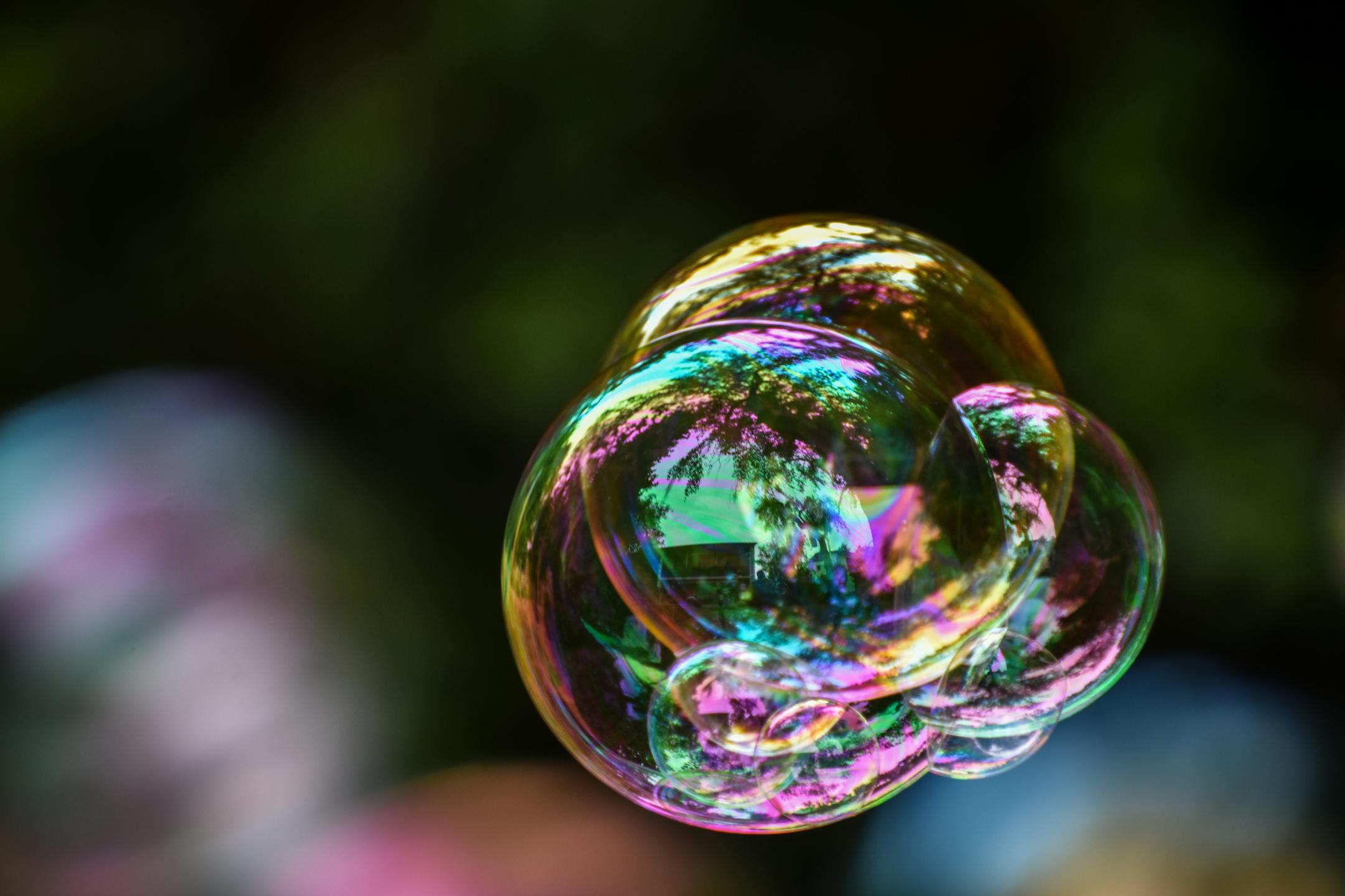 Vibrant iridescent soap bubbles floating outdoors with nature reflections.