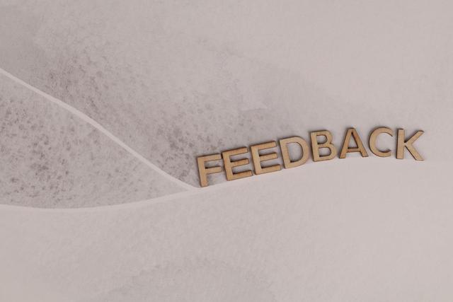 Wooden letters spelling 'FEEDBACK' arranged on textured paper background, conveying a conceptual theme.