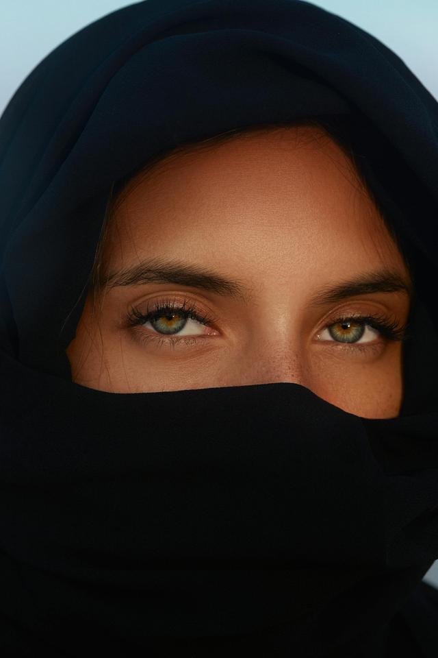 Close-up portrait of a woman with heterochromia wearing a hijab highlighting her unique eyes.
