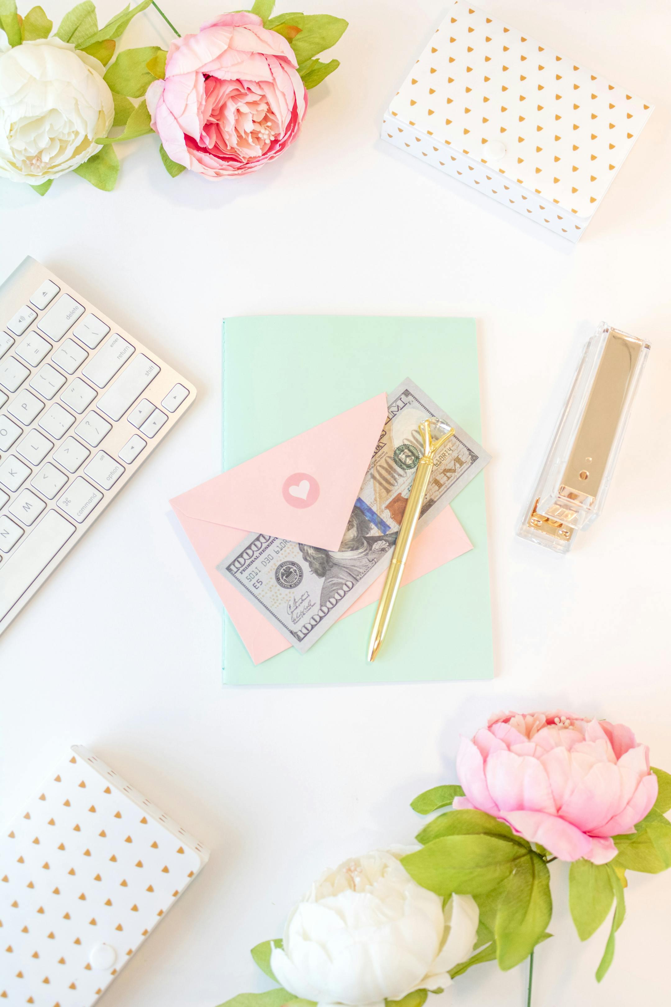 A stylish flat lay with a keyboard, flowers, and stationery on a white background.