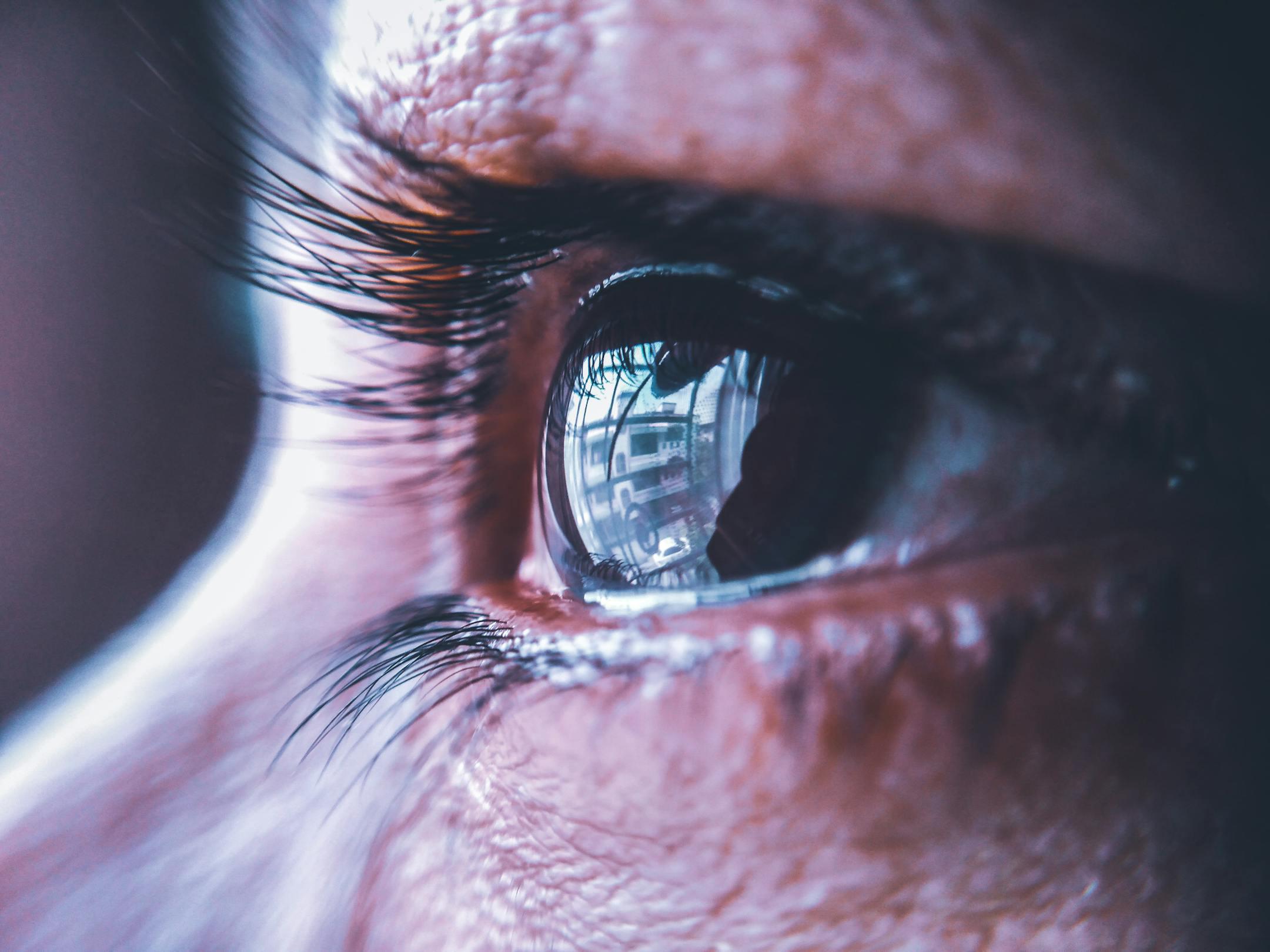 Detailed close-up of an eye reflecting a cityscape, highlighting eyelashes and eye texture.