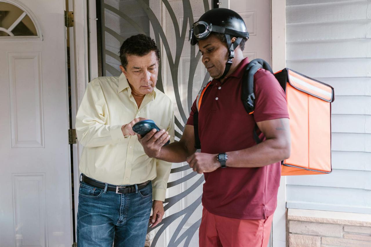 Deliveryman hands a package to a customer at their front door, showcasing efficient logistics.