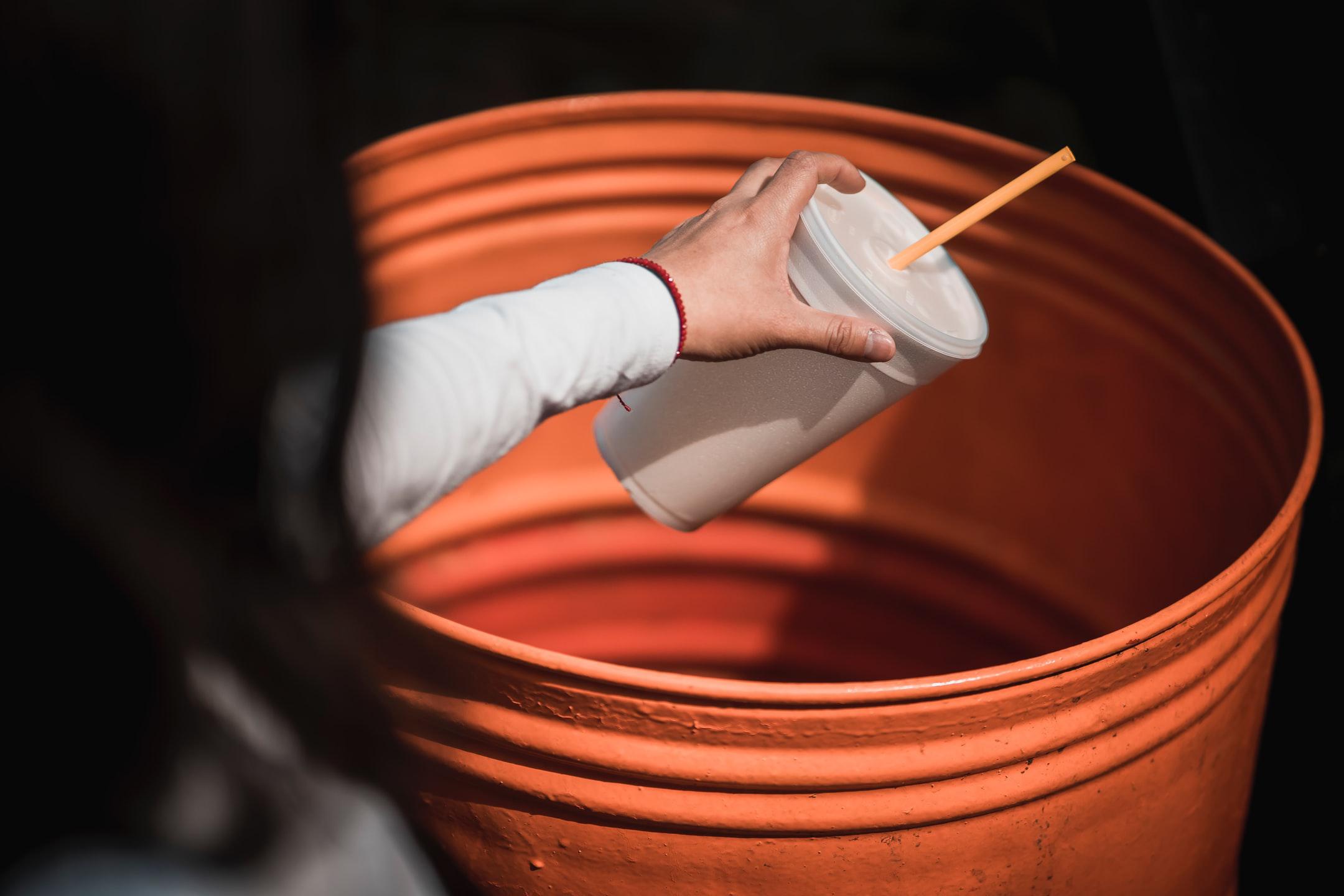 Image of someone throwing away a cup with a high plastic grade.