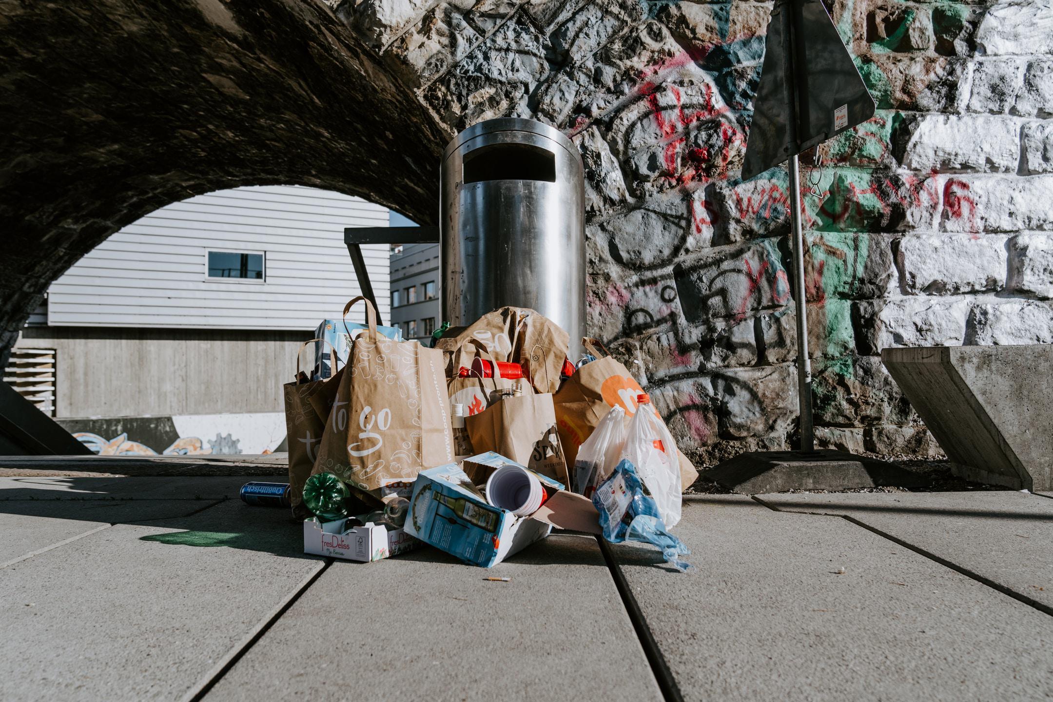 A trash can with trash piled around it.