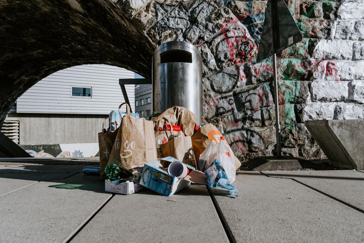 A trash can with trash piled around it.