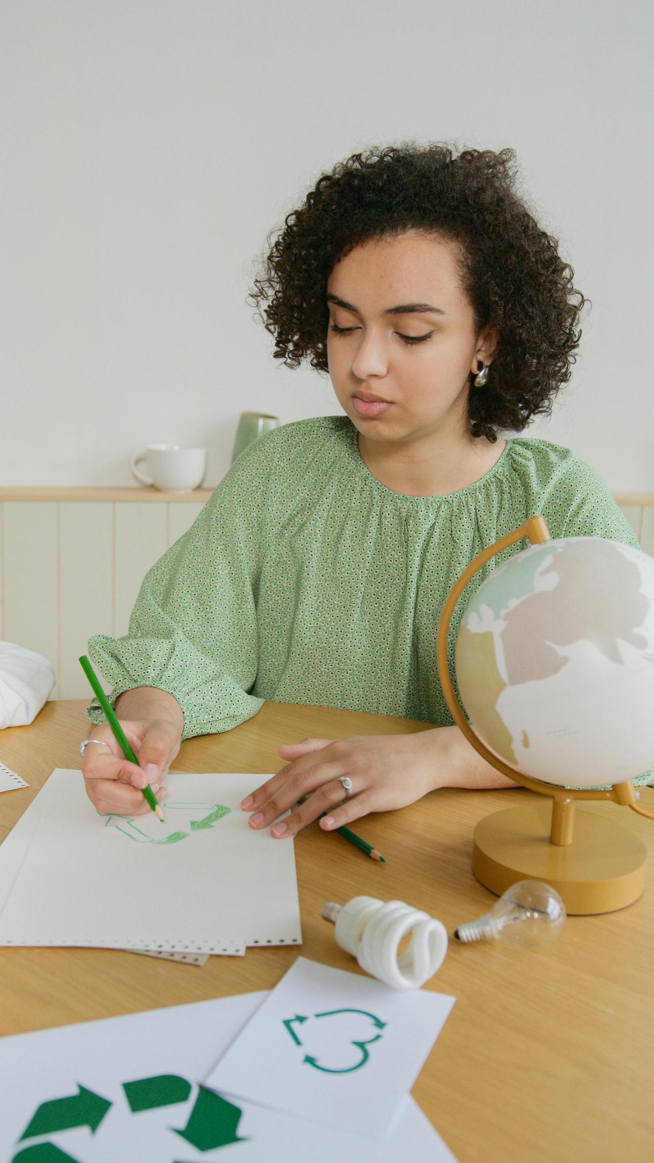 A young woman drawing a recycling symbol, symbolizing sustainable education and environmental awareness.