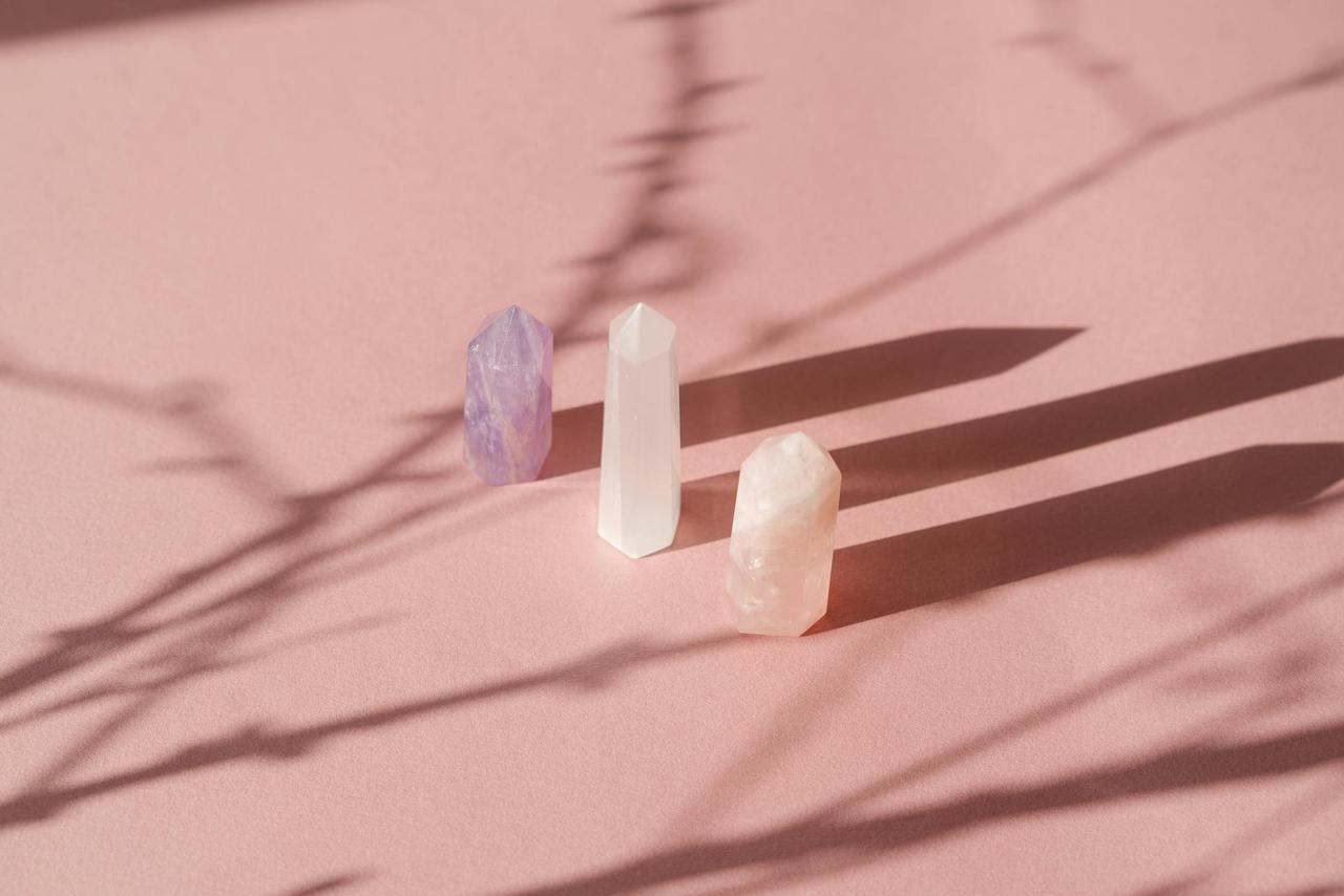 An artistic arrangement of crystals casting shadows on a soft pink background, creating a serene still life composition.