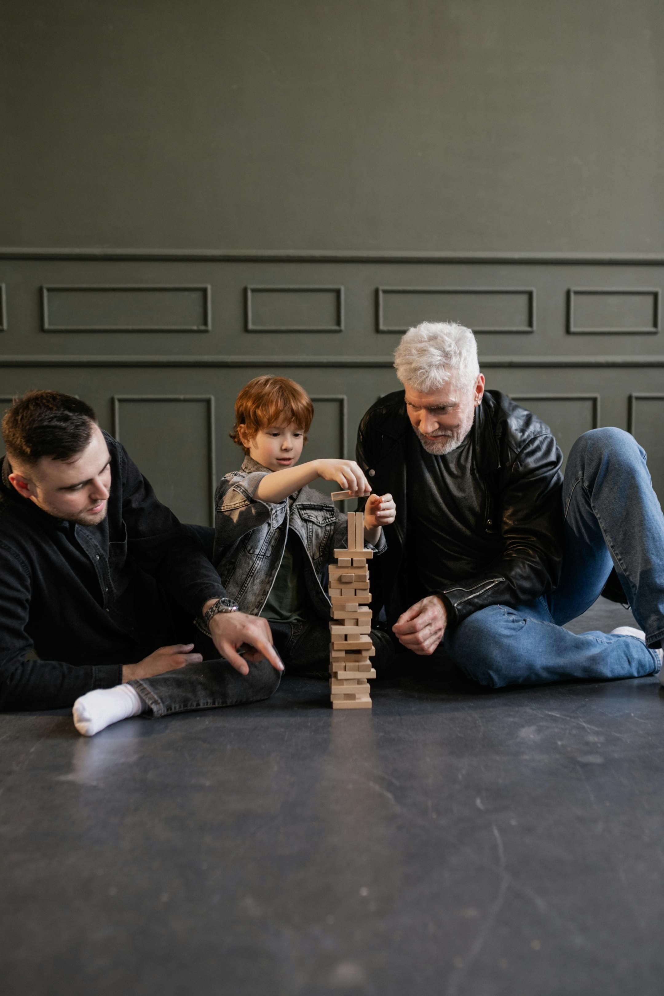Three generations bonding over a game of Jenga indoors, highlighting family fun.