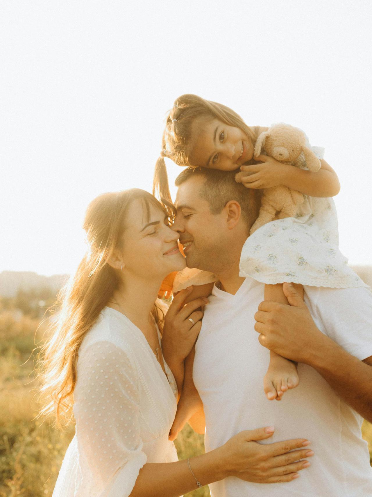 A joyful family of three enjoying a sunny day in a field, radiating love and warmth.