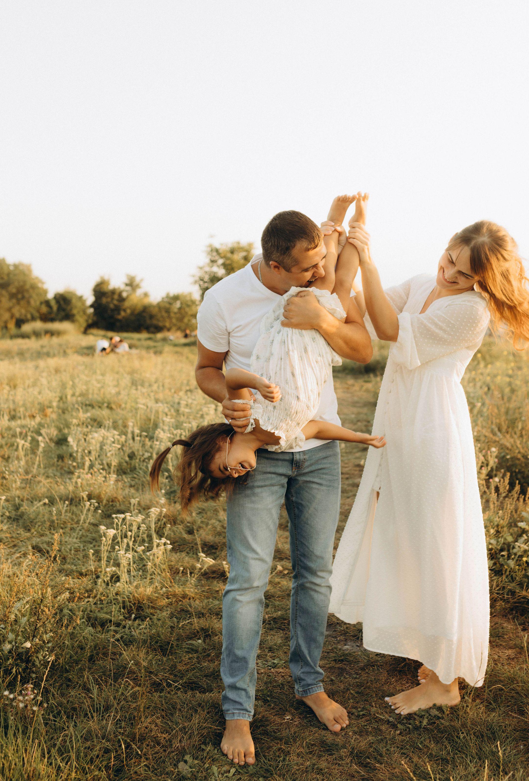 Happy family enjoying playful moments in a sunny field during summer.