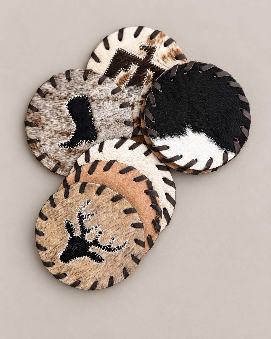 Brazil-made cowhide coasters with leather-laced edges